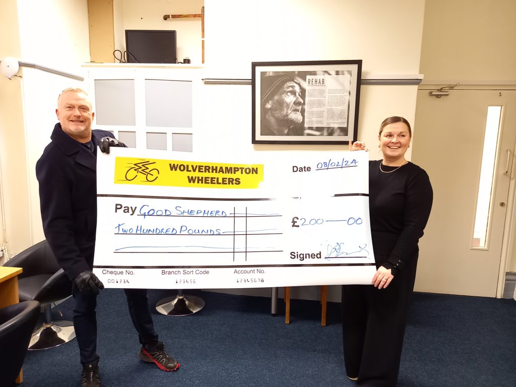 Chris James of Wolverhampton Wheelers and Vicki Smallman from the Good Shepherd charity, in an office, holding an oversized presentation cheque for £200